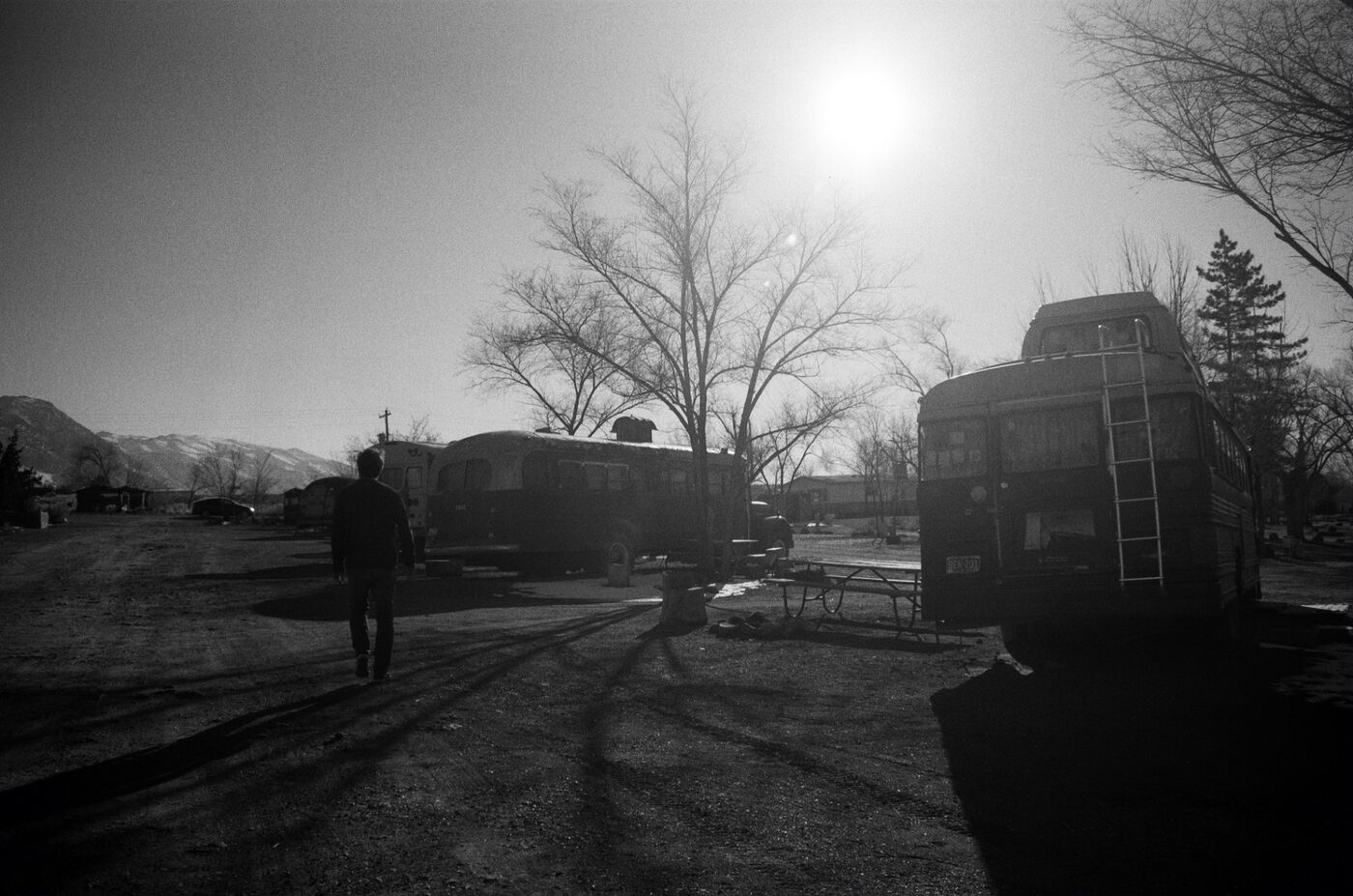 Person walking past buses at sunrise