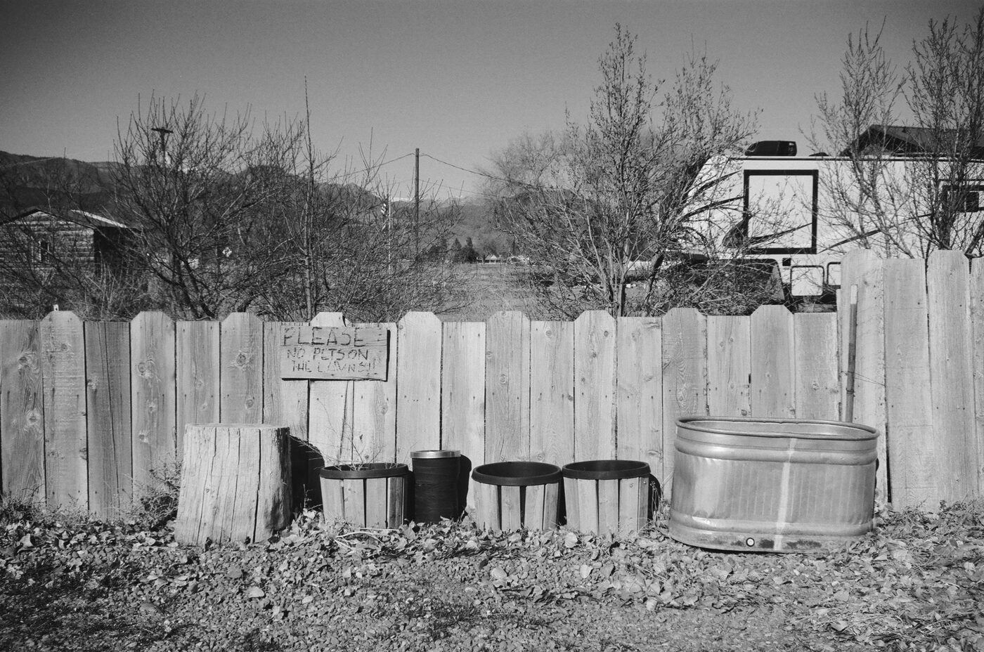 Empty planters lined along a wooden fence with mountains beyond