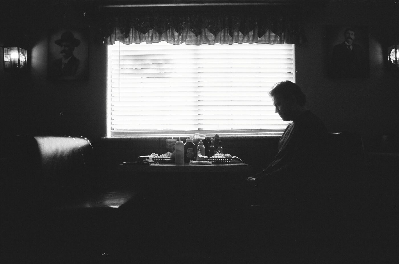 Silhouette of a diner patron beside a bright blinded window