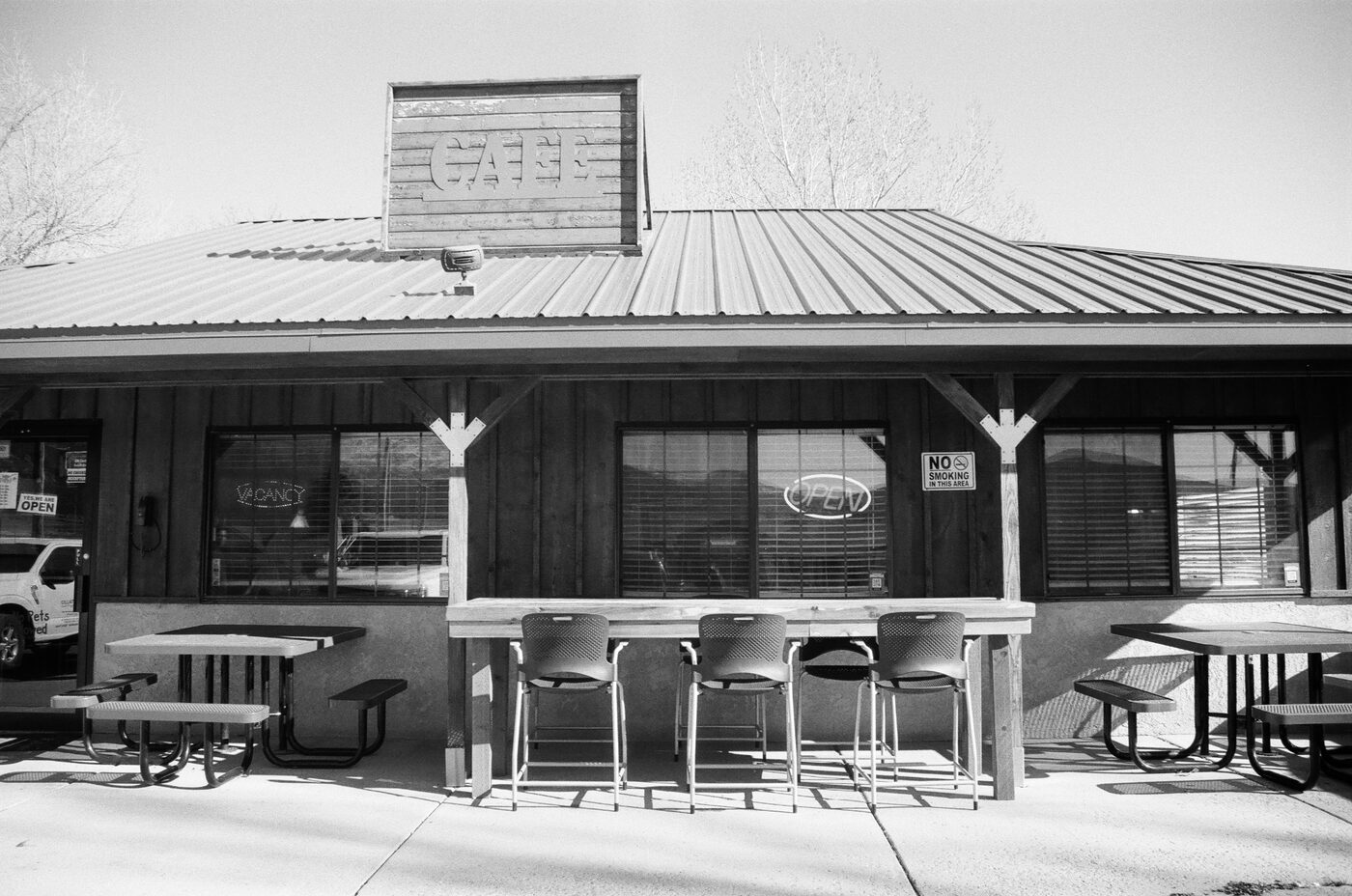 Cafe exterior with stools and picnic tables in afternoon light
