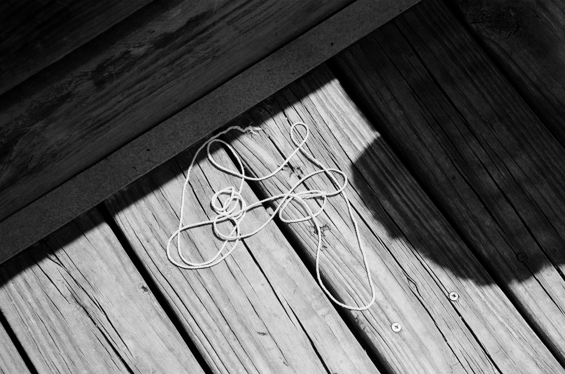 Coiled rope on weathered wooden planks in hard sunlight
