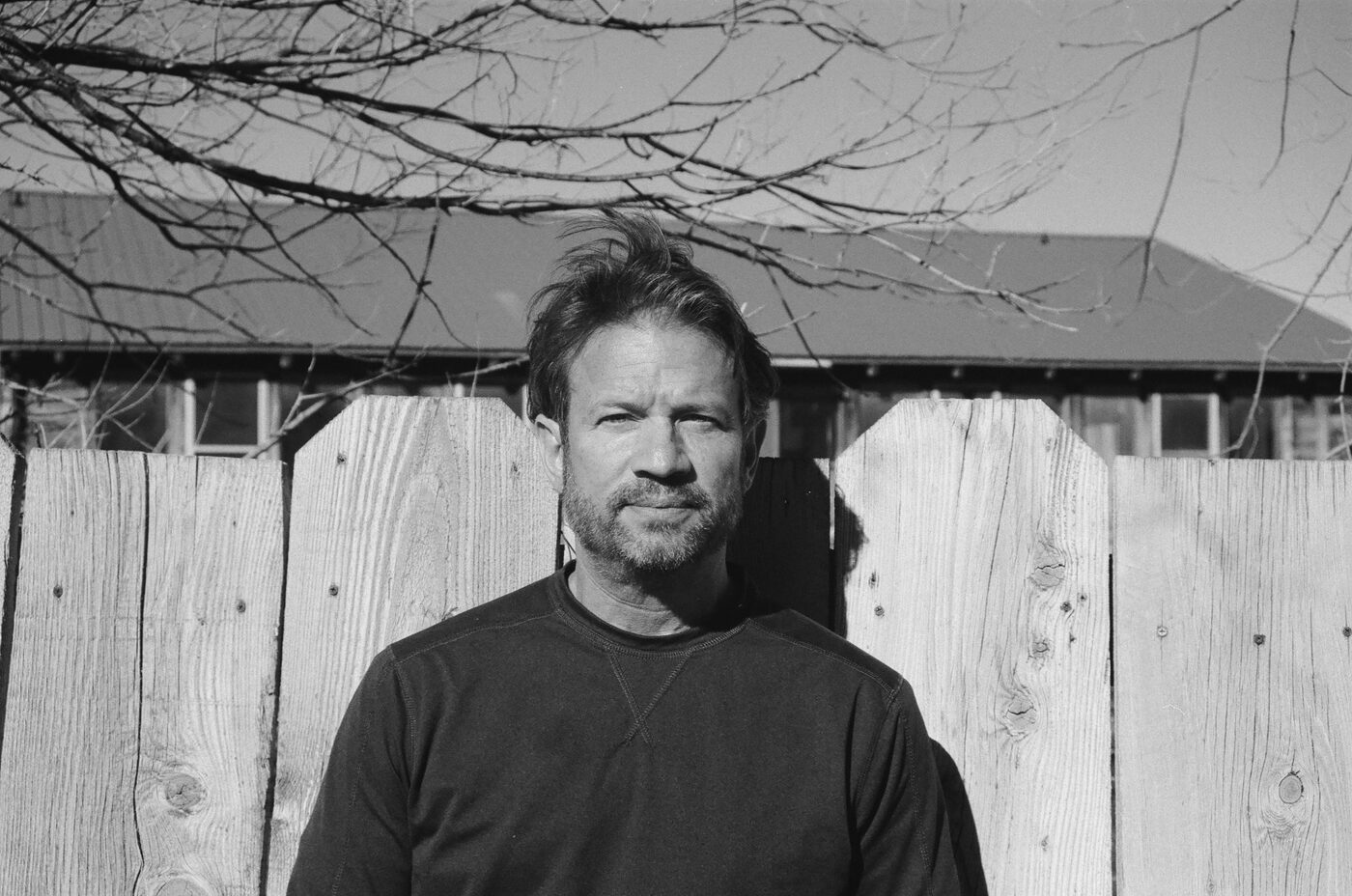 Portrait of a man against a weathered fence