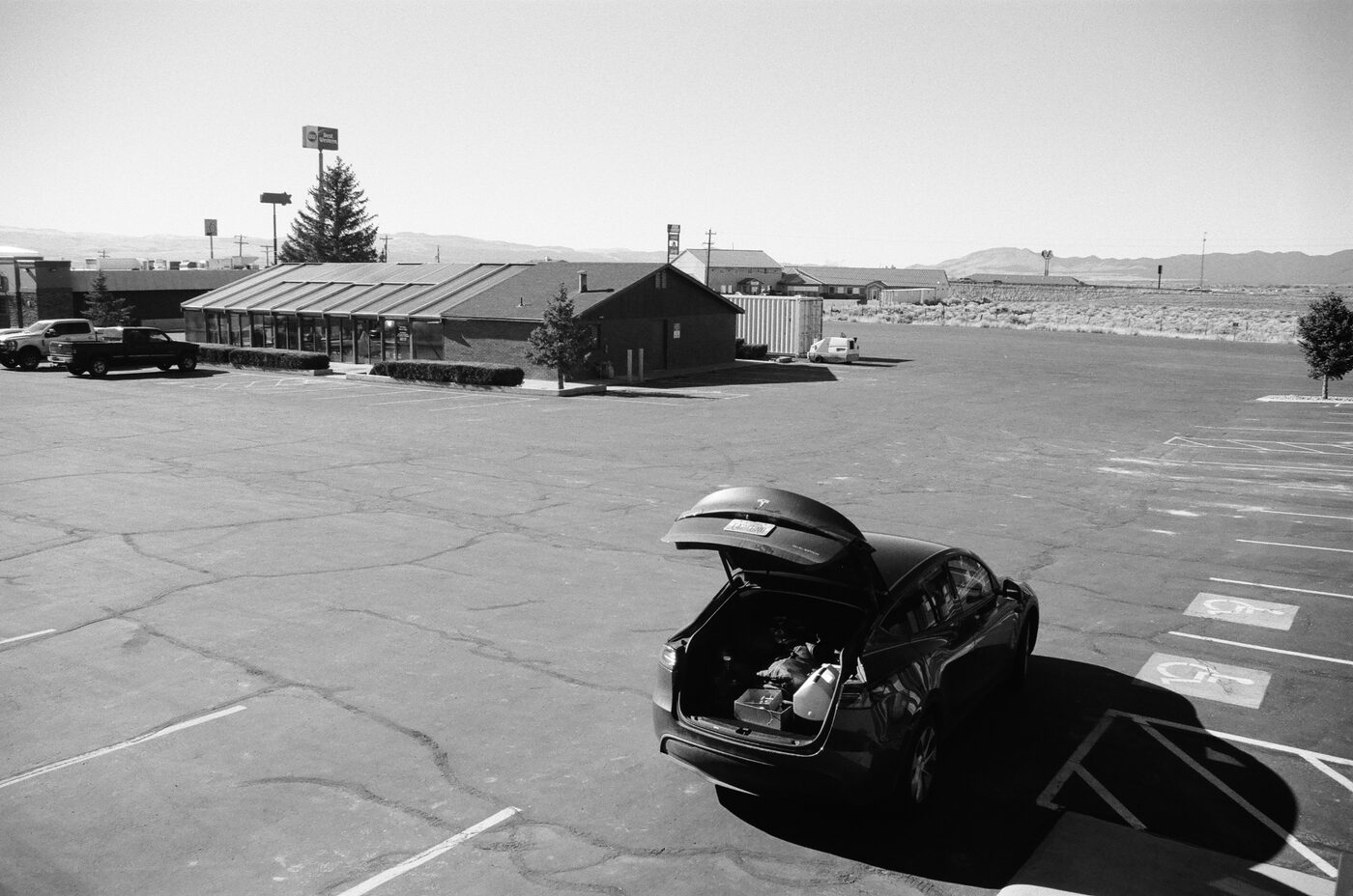 Black car with open trunk in a bright empty parking lot